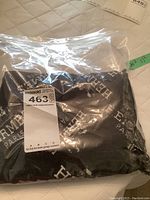 Scarf folded inside sealed plastic bag, showing MaxSold tag and overall black background with white lettering