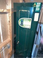 Full view of green Stack-On security cabinet in basement against wood framing