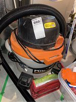 Shop vacuum from the top showing the hose, power cord, and body with RIDGID logo and sticker with auction lot info.