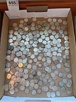 Wide overhead view of box containing numerous silver Canadian quarters
