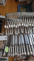 Overall view of rows of dinner forks, teaspoons, and butter spreaders on table