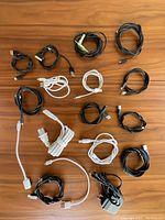 Photo of assortment of 14 charging cords in black and white, coiled or bundled, with various USB, Lightning, micro-USB, and 30-pin connectors.