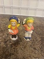 Front and side view of the ceramic cowboy and cowgirl salt and pepper shakers showing details in facial features, clothing colors, and posture.