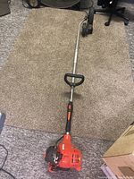 Full view of the Echo PE-225 power edger lying on carpet, showing the red gas engine, straight shaft, and handle grip.