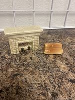Front view of the two ceramic salt and pepper shakers, fireplace and wood log, on countertop.