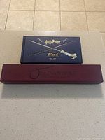 Photo of the Harry Potter wand in an Ollivanders box alongside the Wand Collection hardcover book.