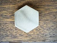 Close-up photo of a hexagon shaped brushed nickel knob showing the front face and brushed texture.