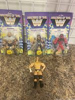 Frontal view of four WWE Masters of the Universe action figures, 3 in packaging and one loose figure of Triple H.