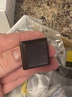 Close-up image of one square-shaped metal knob showing oil rubbed dark finish with copper tones and brushed texture.