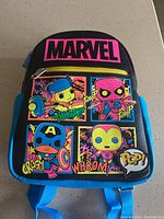 Front view of black mini backpack with colorful Marvel pop art character patches and Marvel logo