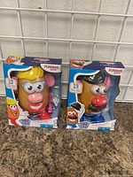 Front view of new Mrs. Potato Head and Mr. Potato Head toy boxes with clear packaging showing the figures.
