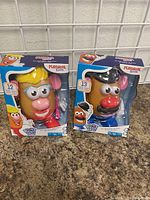 Two new Mr. and Mrs. Potato Head toys in their original Playskool Friends packaging, displayed side by side on a countertop.