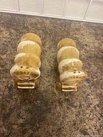 Top-down view of two ceramic stagecoach shakers showing the dispensing holes and wear on the bottom.