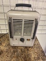 Front view of White-Westinghouse space heater showing dial control, power switch, ventilation grille, and handle.