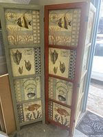 Two-panel wooden folding room partition with framed marine life illustration panels including fish and shells.