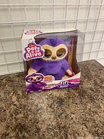Photo of a Zuru Pets Alive Fifi Sloth plush toy in retail packaging on a counter, showing toy and box front with brand and character name.