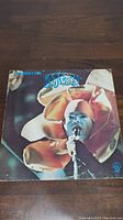 Front cover of Genesis Presenting Genesis vinyl record album showing band member in a flower costume singing