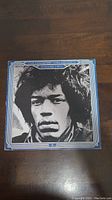 Front cover of vinyl record featuring Jimi Hendrix's black and white portrait with blue and white border text.