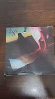 Front cover of Styx 'Cornerstone' vinyl LP album showing artwork with a person on sand at dusk or night.