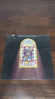 Front cover of The Alan Parsons Project album The Turn of a Friendly Card, showing stained glass playing card artwork.