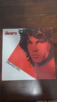 Front cover of The Doors Greatest Hits vinyl album showing Jim Morrison in red tone with band logo and album title