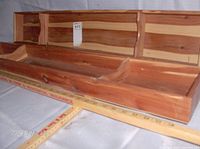 Photo showing two solid cedar trays positioned on a table with measuring sticks indicating length and width. Both trays have three compartments each and a natural wood finish.