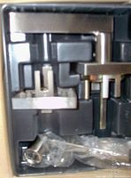 Photo of new satin nickel door handles in black plastic molded holder with hardware in plastic bag.