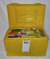 Yellow hard plastic case open showing assortment of hand tools including pliers, screwdrivers, and tape inside case trays.