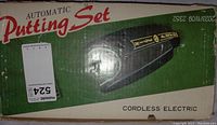 Photo of the original box labeled 'Automatic Putting Set' showing product name and noting cordless electric feature