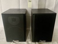 Front view of two Braxton bookshelf speakers with black fabric grilles in place, showing Braxton logos at bottom.