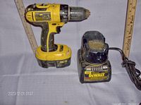 Photo of the DeWalt 18V cordless drill with attached battery pack and separate battery charger unit with power cord.