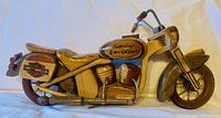 View of left side of wooden model motorcycle showing Harley Davidson logo on tank and side case.