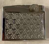 Front side showing textured silver metal finish with Fleur-de-lys design.