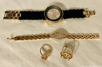 Photo showing all 5 items: wristwatch, two bracelets, two rings arranged on a flat surface.