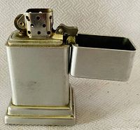 Clear side view of the vintage metal lighter with open lid showing perforated chimney and ignition wheel.