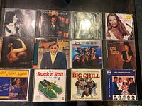 Photo showing 12 music CDs, arranged on table, featuring various cover arts including artists Sting, Chet Baker, and Atlantic Starr.