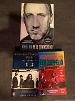 Photo showing three autobiographical music books: 'Who I Am' by Pete Townshend, 'Unforgettable Fire: The Story of U2' by Eamon Dunphy, and 'Stairway to Heaven: Led Zeppelin Uncensored' by Richard Cole with Richard Trillo.