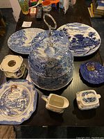Photo showing the 9-piece blue and white china set including the 3-tier cake tray, two oval platters, and smaller serving pieces arranged on a table.