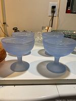Set of four blue frosted glass dessert bowls shown from an angled view on table.