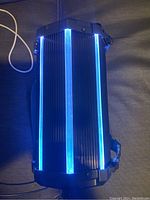 Top down view of black Sylvania Bluetooth speaker showing bright blue LED light strips on the ribbed black casing.