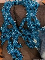 Turquoise tinsel garland, shiny and reflective strands arranged with ambient lighting on dark fabric background