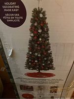 Front photo of original box showing decorated slim artificial Christmas tree with integrated lights and hinge style.