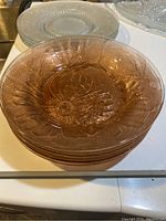 Stack of pink depression glass soup bowls showing translucent pink glass and floral pressed glass pattern