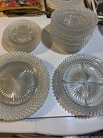 Top view of stacked clear depression glass plates and bowls showing hobnail and starburst patterns