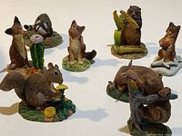 Wide view showing 8 woodland animal figurines arranged on white background