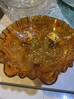 Top-down view showing the iridescent amber carnival glass with raised rose and leaf patterns inside the bowl.