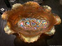 Top view of large amber carnival glass bowl showing ruffled edges and central pear design.