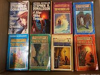 Top-down view of all eight novels by Stephen R Donaldson arranged in two rows. Titles and covers visible.
