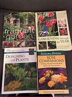 Photo shows four gardening books laid flat: 'The Fragrant Garden', 'Gardening through the Year', 'Designing with Plants', and 'Rose Companions'. Covers show flowers and garden scenes.
