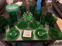 Four tall green pressed glasses, six smaller green pressed glasses, six green pressed glass dessert plates, one pedestal candy jar with lid, and one small green bowl.